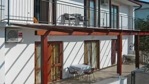 A two-story building with a balcony on the upper floor, featuring a table and chairs. - Holiday Home in Starigrad With Sea Views (Starigrad)