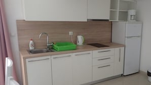 A modern kitchen with white cabinets, a sink, a green dish rack, a coffee maker, and a refrigerator. - Holiday Home in Starigrad With Sea Views (Starigrad)