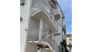 A multi-story building with a central staircase, balconies, and potted plants. - Apartment in Biograd Near Drazica Beach (Biograd na Moru)