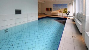 A swimming pool with tiled walls and a bench in the background. - Appartement in Westerland auf Sylt (Sylt)