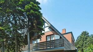 A two-story brick building with a sloped roof, a wooden fence, and a sign indicating it is an apartment complex in Berlin. - Appartement in Westerland auf Sylt (Sylt)