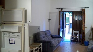 Un soggiorno con divano, un tavolino e una televisione. Una porta dà accesso a una zona esterna.
