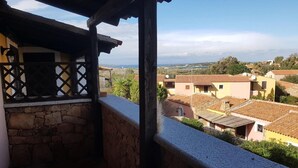 Un balcone con pareti in pietra e vista su edifici con tetti in terracotta in un contesto rurale.