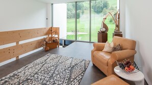 Una sala de estar moderna con un ventanal grande, un banco de madera, un sofá de cuero y una alfombra estampada.