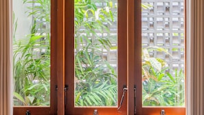 A window with wooden frames and a view of greenery outside. - Nala Villa by Betterplace (Canggu)