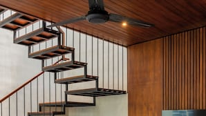 A modern living room with a wooden staircase, a flat-screen TV, and a sofa. - Nala Villa by Betterplace (Canggu)
