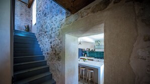 A staircase leading to a kitchen with a stone wall, wooden stools, and a modern light fixture. - Rustic 4-bedroom villa with all the modern amenities in quiet surrounding  (Croatia)