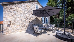 A stone building with a patio featuring two sofas and a large umbrella. - Rustic 4-bedroom villa with all the modern amenities in quiet surrounding  (Croatia)