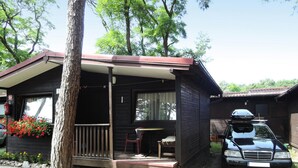 A small cabin with a covered porch, a dining area, and a car parked outside. - Holiday Resort in Dziwnowek - Polaris by the sea (Dziwnów)