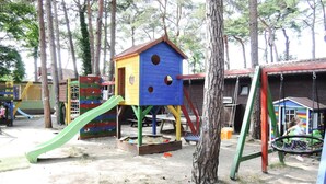 A playground with a blue playhouse, a slide, and a swing set. - Holiday Resort in Dziwnowek - Polaris by the sea (Dziwnów)