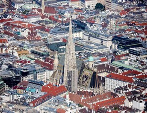 An aerial view of a densely packed urban area with historic architecture, including a prominent cathedral and a large, ornate building with a distinctive facade.