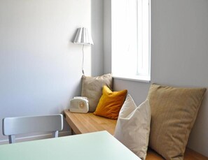 Cozy room with a wooden bench, table, and lamp, offering a bright and airy atmosphere.