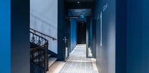 A hallway with a staircase on the left, a patterned floor, and a sign above the door that reads 'URBANAUTS STUDIOS Vienna'. - Urbanauts Studios in Wien (Vienna)