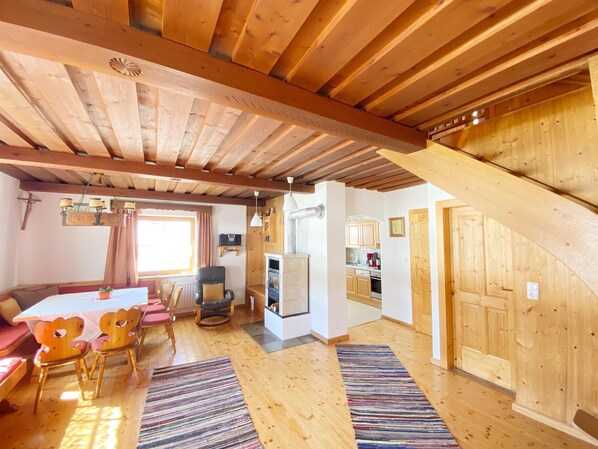 A wooden interior with a dining area, kitchen, and staircase.