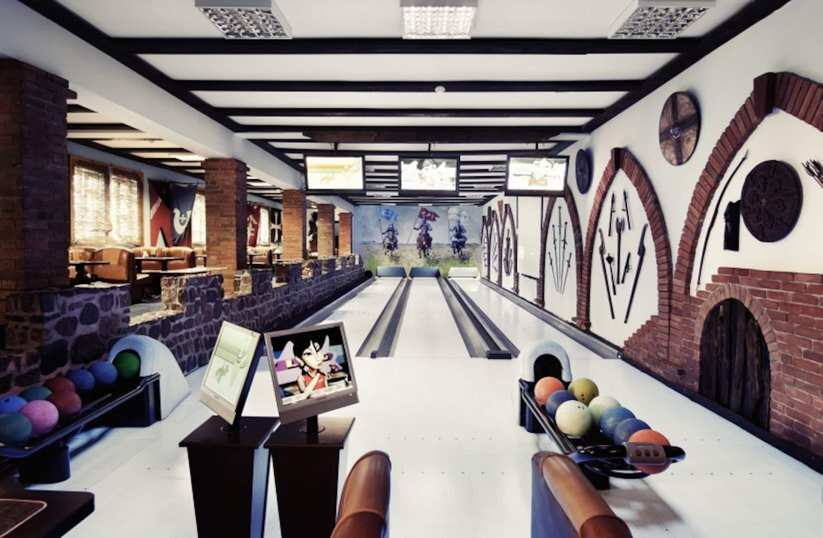 A bowling alley with a modern design, including a bowling lane, pins, and a screen displaying a cartoon character.