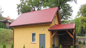 A yellow house with a red roof, a small porch, and a door. - Holiday Home With a Terrace, Right on the Lake (Ryn)