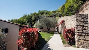 A narrow pathway flanked by stone walls and lush greenery, leading to a building with a tiled roof. - Residence Nautic Resort San Carlo, Gargnano (Gargnano)