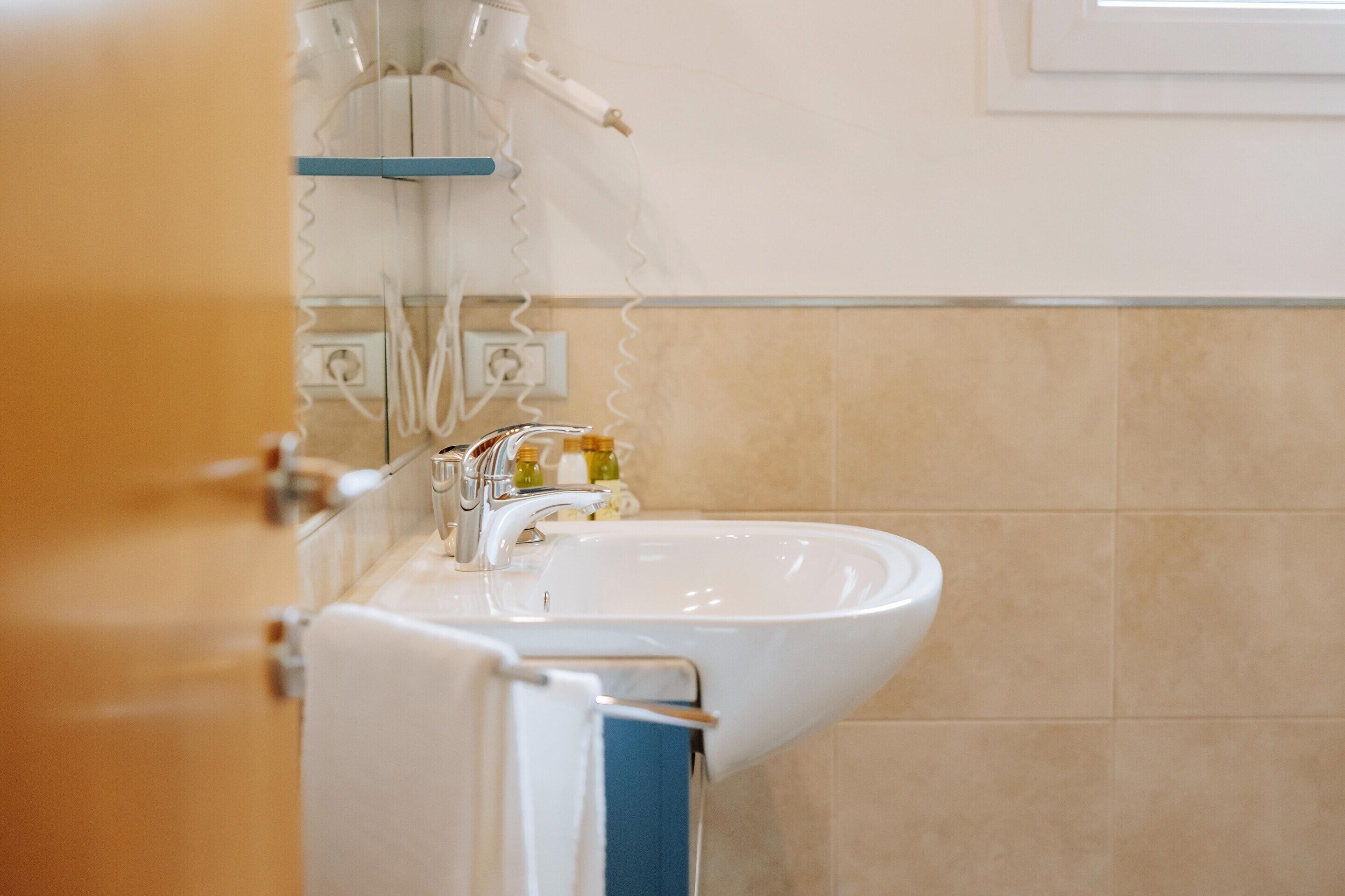 A bathroom with a white sink, a towel rack, and a mirror.