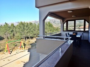 A balcony with a view of a mountainous landscape, a dining area with a table and chairs, and a railing. - Apartment in Rovanjska Near Velebit Mountains (Jasenice)