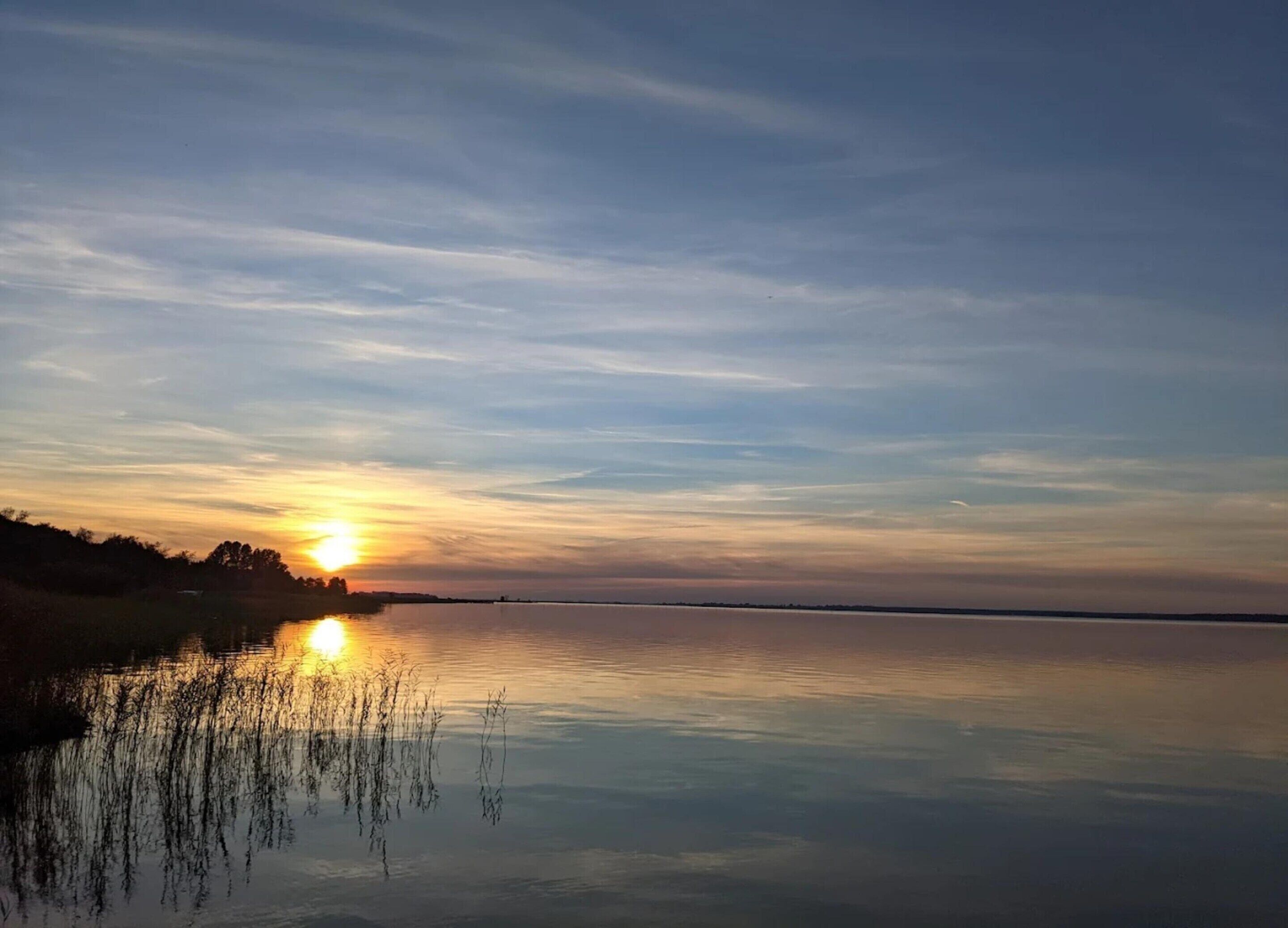 En rolig sø ved solnedgang under en klar himmel.