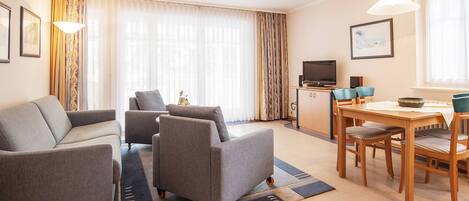 Una sala moderna con sofá, sillones, mesa de comedor y televisor.