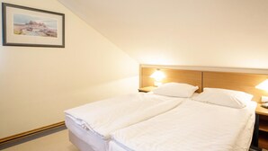 A twin bed with two pillows and a nightstand with a lamp. - Ferienwohnung im Dunenpark Binz (Binz)