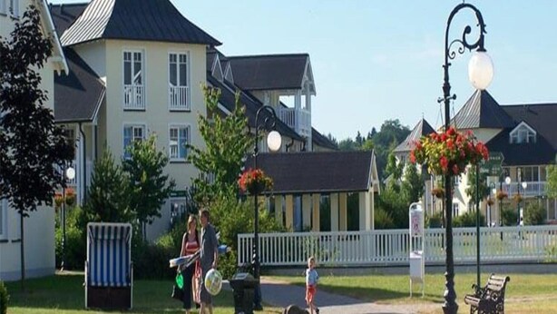 A residential area with houses, a street lamp, and a bench. - Ferienwohnung im Dunenpark Binz (Binz)