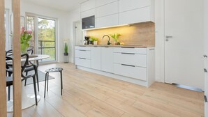 Una cocina moderna con armarios blancos, encimera de madera y televisión integrada.