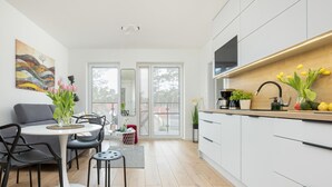 Una cocina moderna con armarios blancos, encimera de madera y un comedor con mesa y sillas.