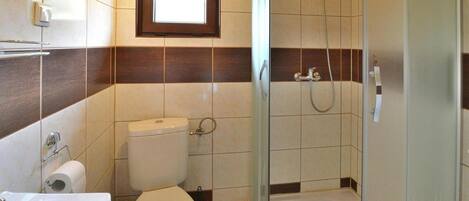 A bathroom with a toilet, bidet, sink, and a glass-enclosed shower.