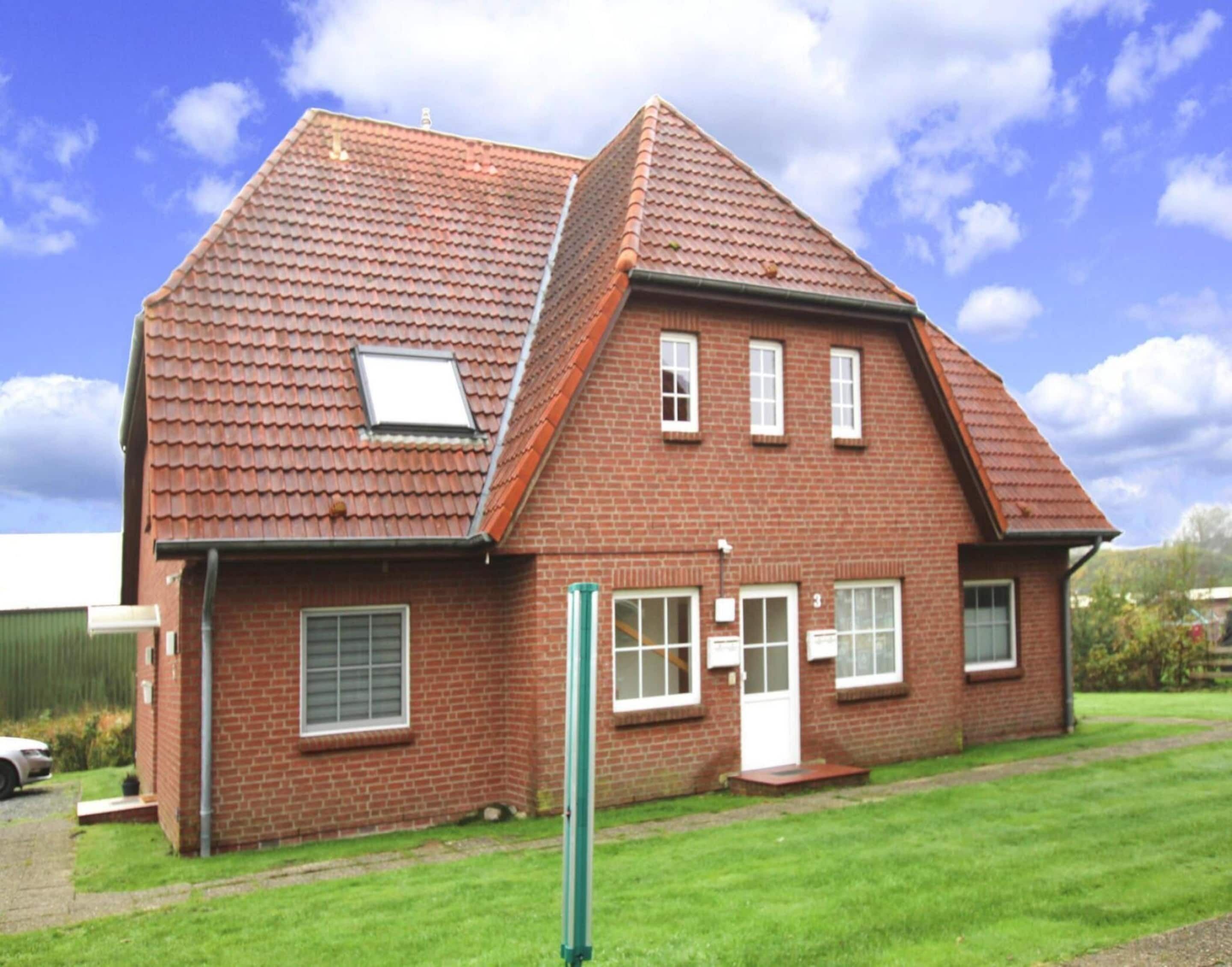A two-story brick house with a sloped roof, a small attached garage, and a front door.