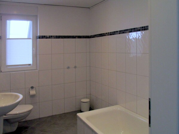 A bathroom with a toilet, sink, and bathtub. - Ferienhaus mit Drei Badern in Dornumersiel (Dornum)