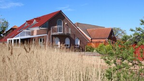 Une grande maison en briques avec un toit rouge, un balcon et une véranda.