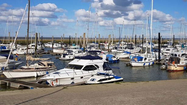 Un port de plaisance où de nombreux bateaux sont amarrés à des quais en bois.