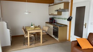 En kompakt bolig med tekøkken, spiseplads og en brun lædersofa.