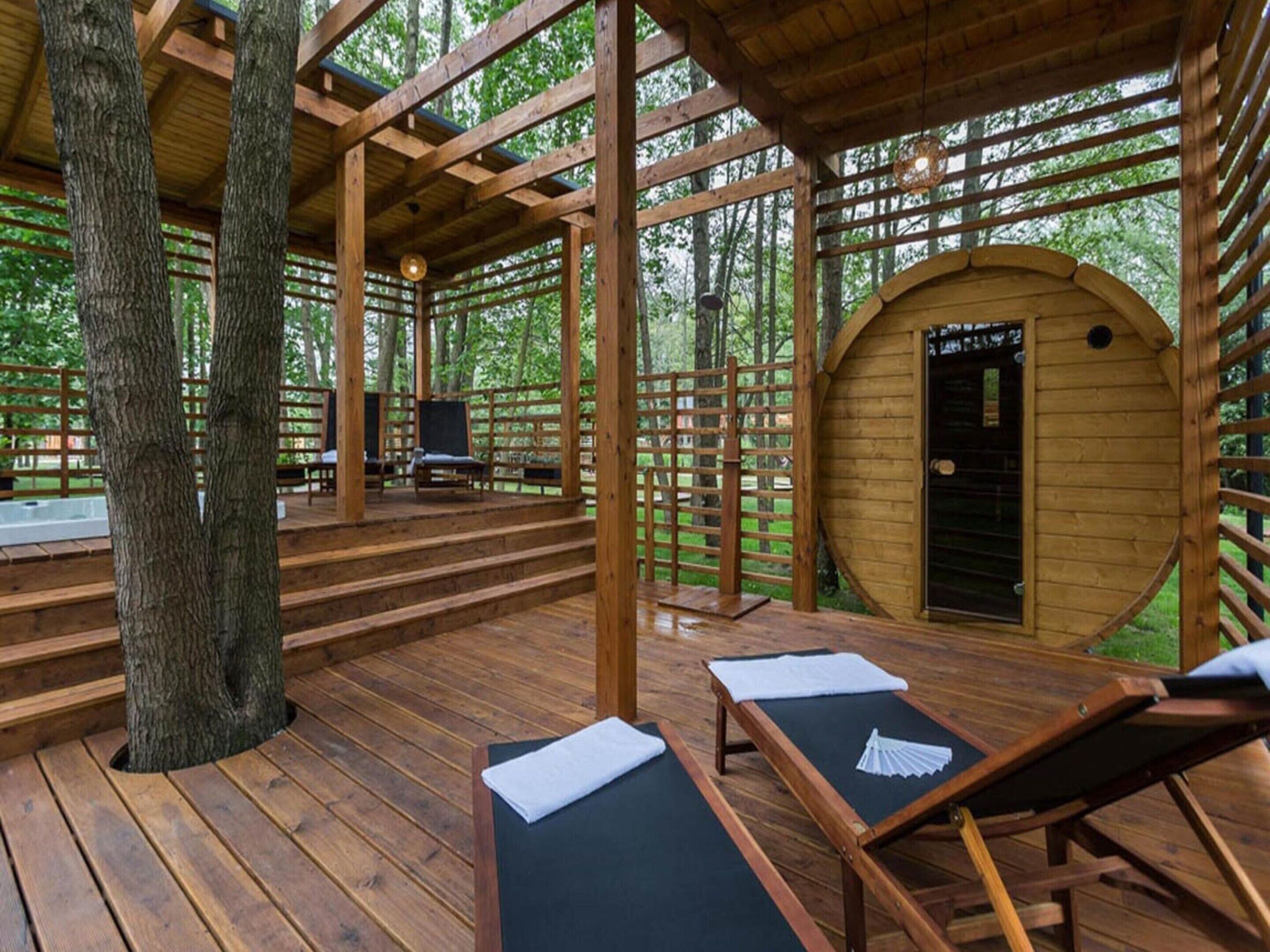 Una terraza de madera con sillones de descanso y una pequeña estructura de madera con una puerta.