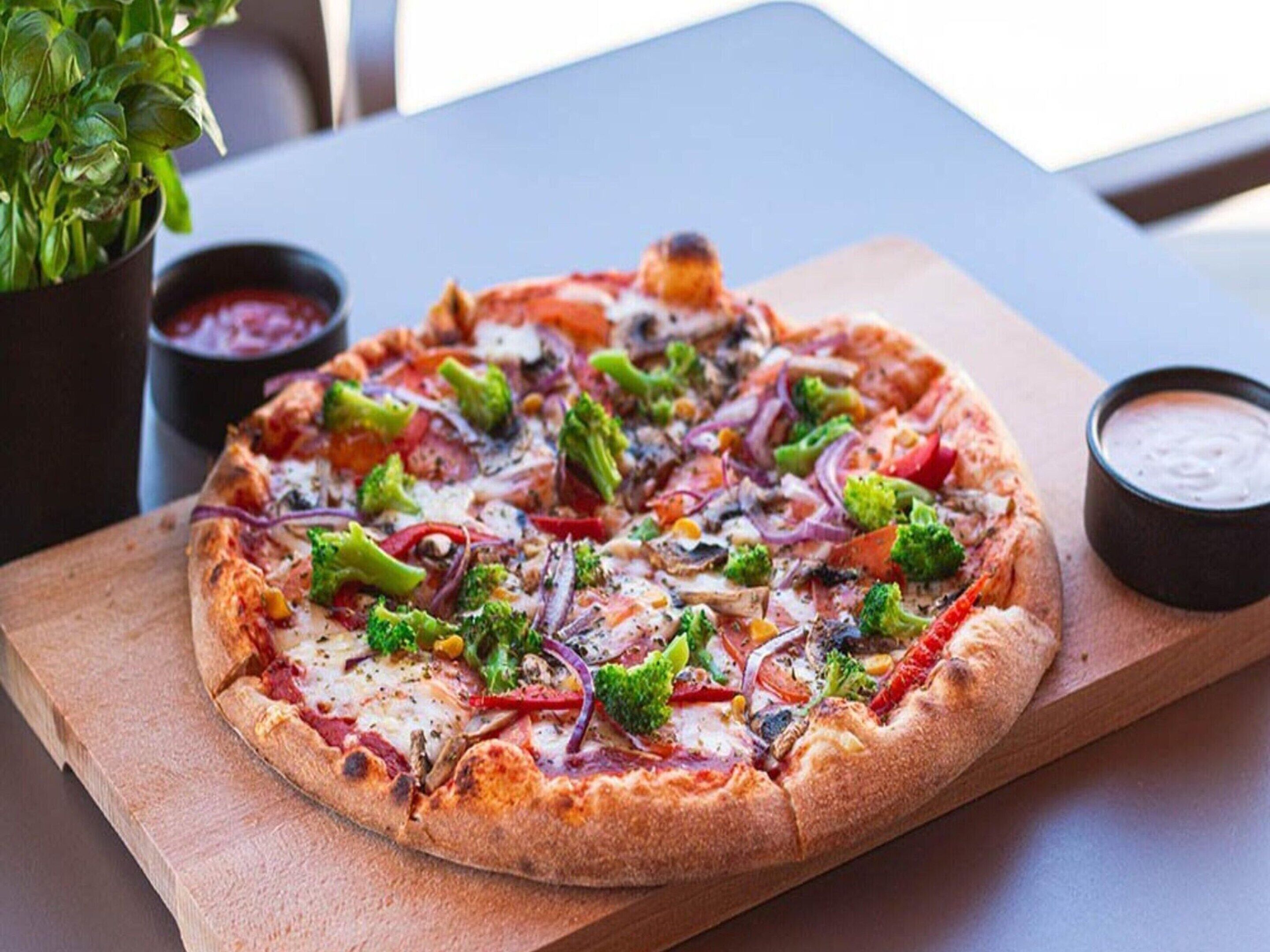 Una pizza con diferentes ingredientes sobre una tabla de madera.