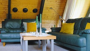 A cozy room with two green leather sofas, a wooden table, and a wooden ceiling. - Ferienpark Tennenbronn (Schramberg)