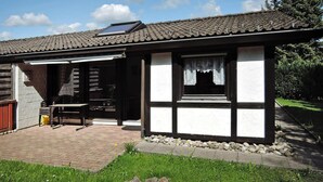 A traditional house with a tiled roof, a wooden door, and a small patio area with a table and chairs. - Ferienpark Tennenbronn (Schramberg)
