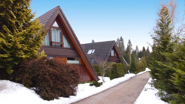 A house with a sloped roof, surrounded by snow-covered ground and trees. - Ferienpark Tennenbronn (Schramberg)
