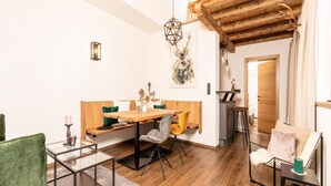 A modern dining area with a wooden table and chairs, a hanging light fixture, and a staircase leading to an upper level.