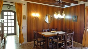 Een eethoek met een houten tafel en stoelen, een kroonluchter en een spiegel aan de muur.
