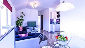 Ein modernes Wohnzimmer mit einer Couch, einem Glastisch und einem Fernseher.
