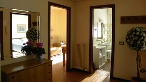 Una habitación de hotel con un aparador de madera, un espejo, un radiador y una planta en maceta.
