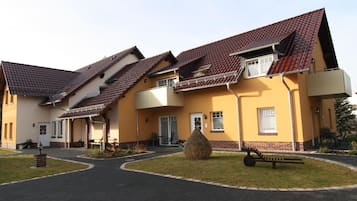 A residential building with multiple balconies, a paved driveway, and a well-maintained lawn.