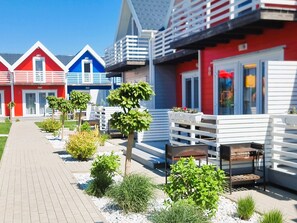 A row of colorful seaside cottages with a paved walkway and small plants. - Cottage in Sarbinowo Near Seaside Beach (Mielno)