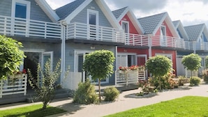 A row of modern, two-story houses with white balconies and red and grey exteriors. - Cottage in Sarbinowo Near Seaside Beach (Mielno)
