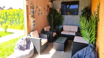 An outdoor seating area with wicker furniture, a television, and a view of the outdoors.