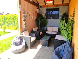 An outdoor seating area with wicker furniture, a television, and a view of the outdoors.