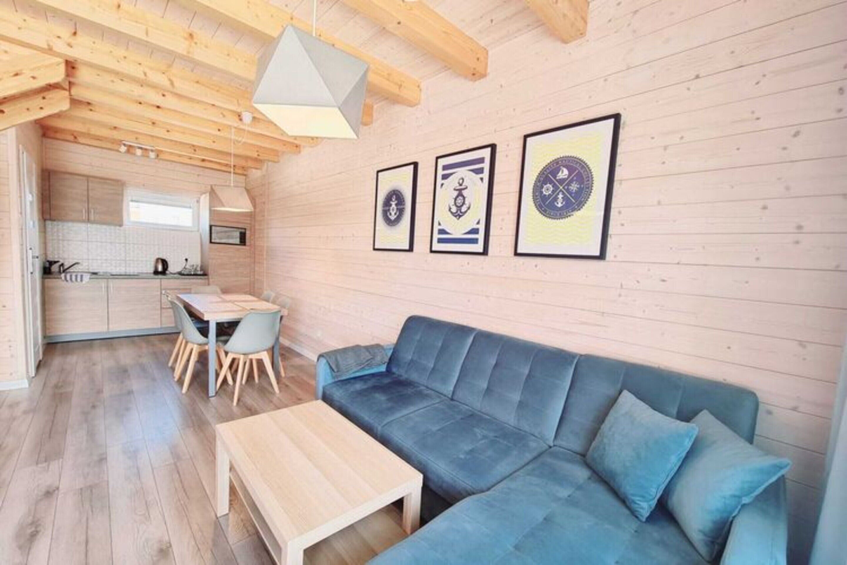 A modern living room with a blue sofa, wooden coffee table, and a dining area with a table and chairs.